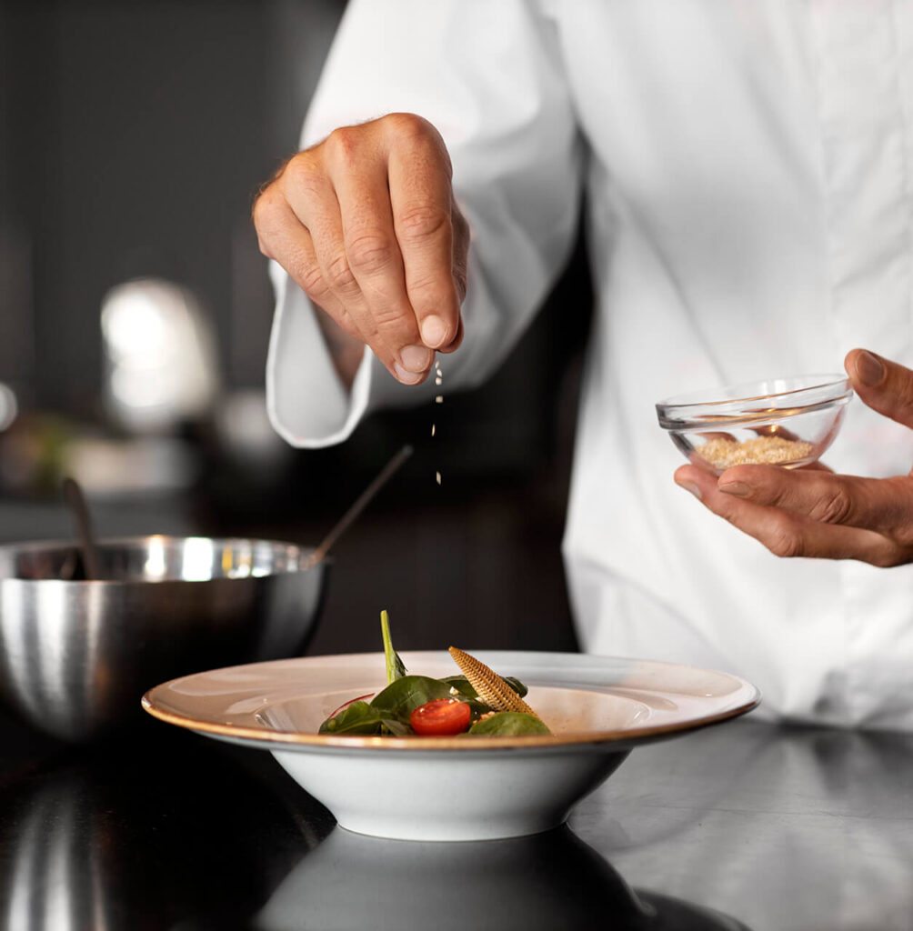 Chef topping salt over prepped dish.